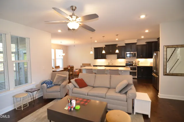 a living room with furniture kitchen view and a large window