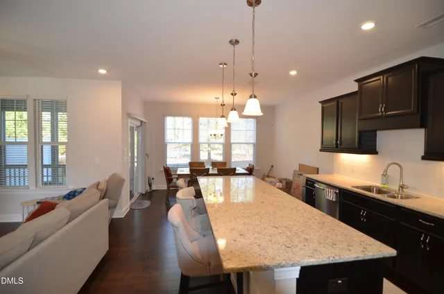 a large kitchen with granite countertop a stove a sink a dining table and chairs