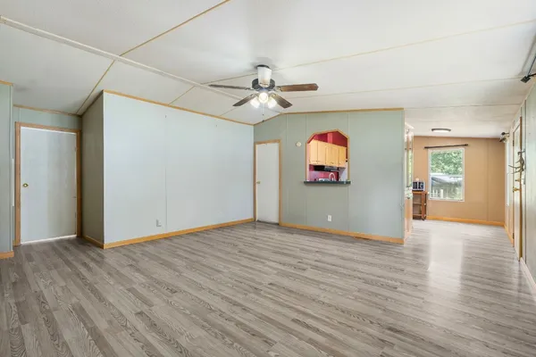 an empty room with wooden floor chandelier fan and windows