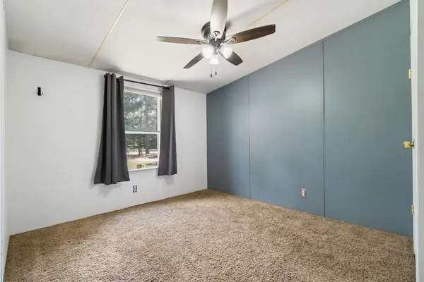 an empty room with windows and fan