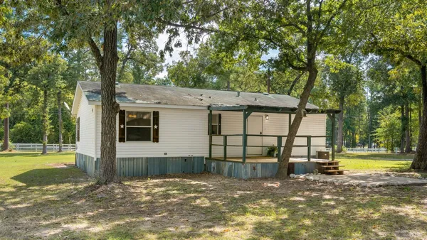 a view of a house with a yard and a large tree