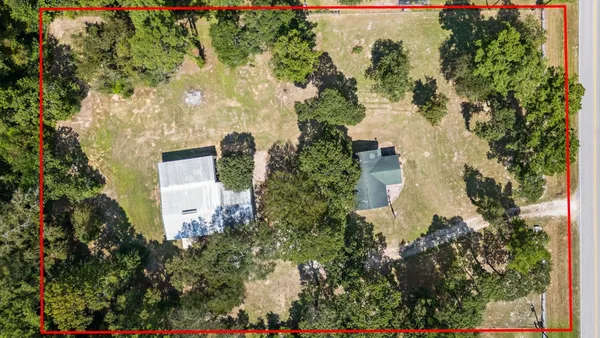 an aerial view of residential house with outdoor space and trees all around