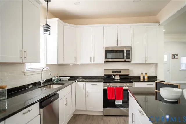 a kitchen with stainless steel appliances granite countertop a sink a stove and a microwave