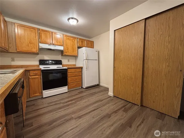 a kitchen with stainless steel appliances granite countertop a refrigerator a sink dishwasher and wooden cabinets with wooden floor