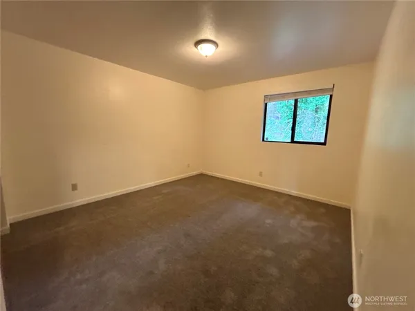 an empty room with a ceiling fan and window