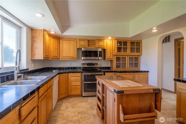 a kitchen with granite countertop a refrigerator and a stove top oven