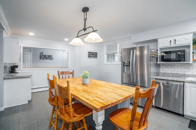 a dining room with stainless steel appliances a table chairs and chandelier