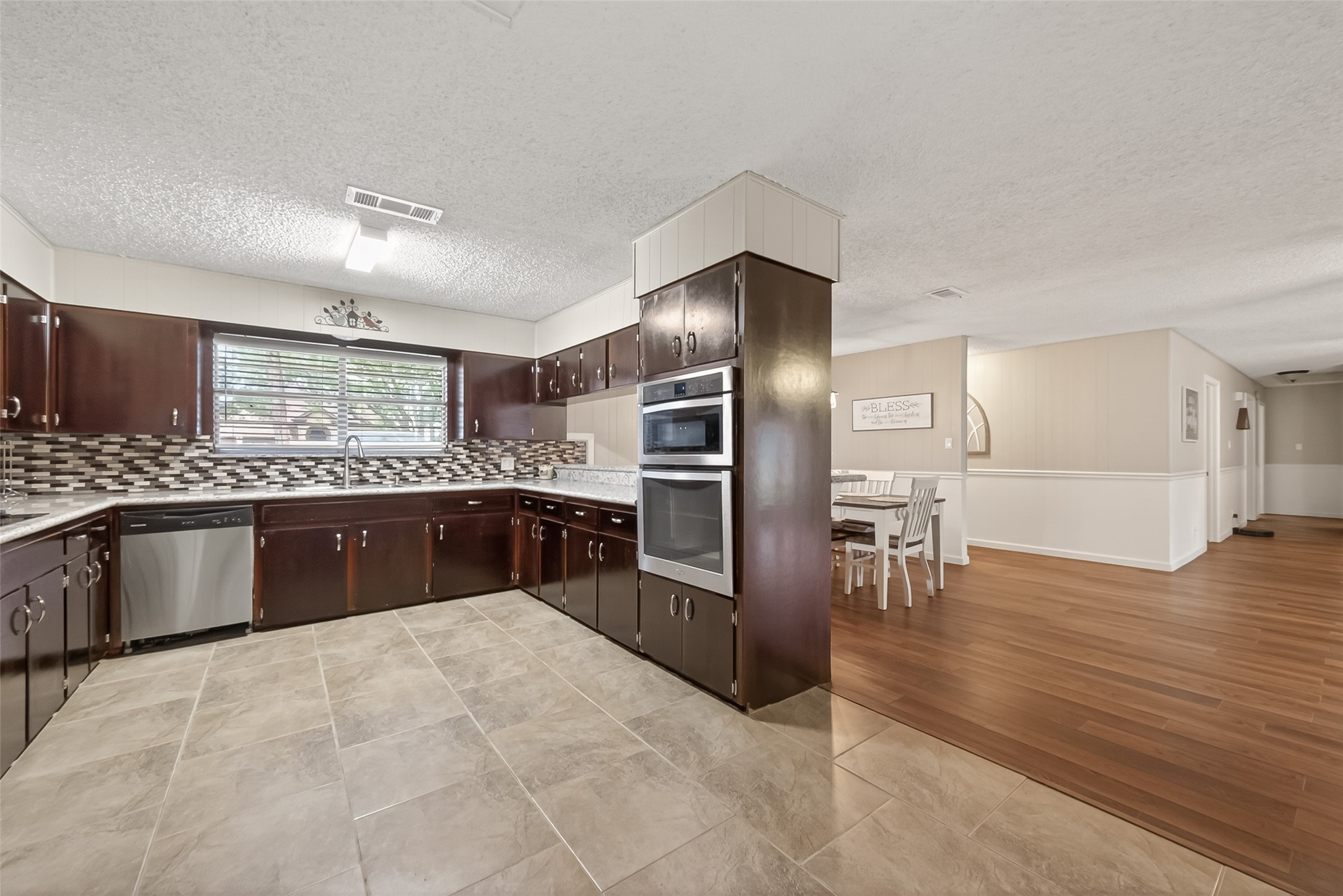 9525 Gene Street Needville, TX 77461 - Photo 16 of 48 a large kitchen with stainless steel appliances a large counter top a stove a chimney a sink and a refrigerator
