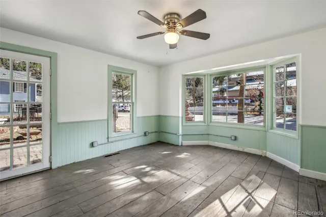 a view of an empty room with window and wooden floor