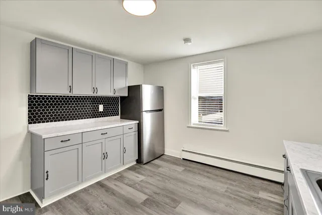 a kitchen with a refrigerator and white cabinets