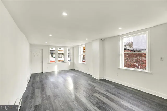 a view of a big room with wooden floor and windows