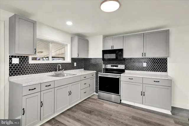 a kitchen with granite countertop a sink cabinets and stainless steel appliances