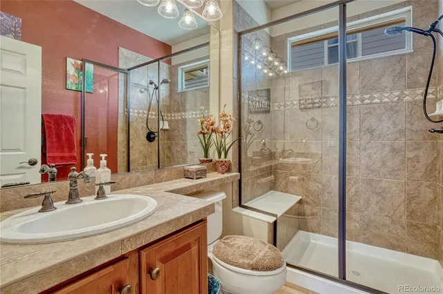 a bathroom with a granite countertop sink toilet a mirror a vanity and shower