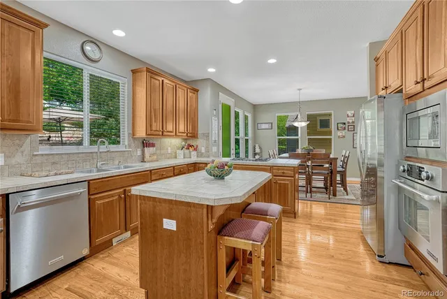 a kitchen with stainless steel appliances granite countertop a sink a stove and a wooden floors