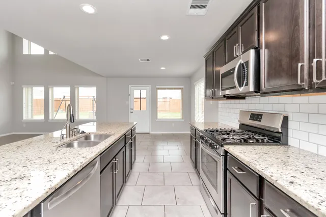 a kitchen with stainless steel appliances granite countertop a sink stove and cabinets