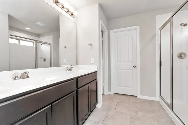 a bathroom with a double vanity sink a mirror and a shower