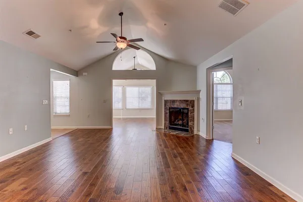 an empty room with wooden floor fireplace and windows