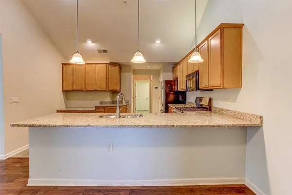a large kitchen with granite countertop a sink a counter top space and cabinets