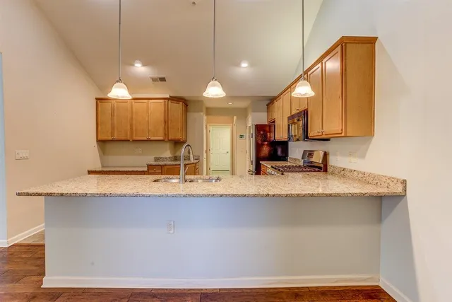 a large kitchen with granite countertop a sink a counter top space and cabinets