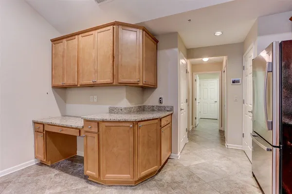a view of kitchen with granite countertop cabinets and refrigerator