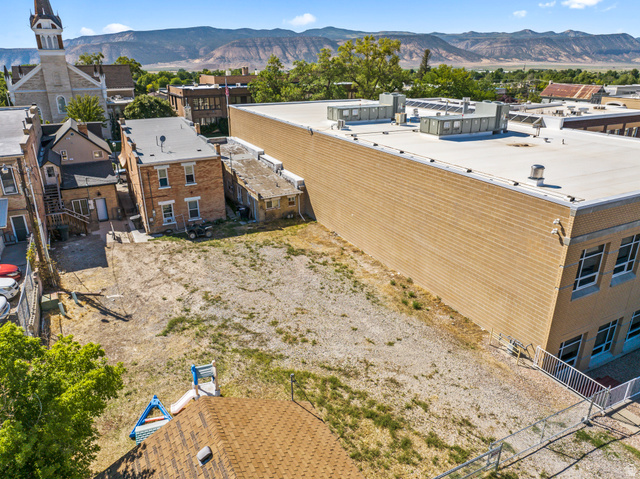 69 South Main Street Manti, UT 84642 - Photo 10 of 44 Expansive gravel lot offering significant development potential, flanked by a multi-story brick building and a larger commercial structure