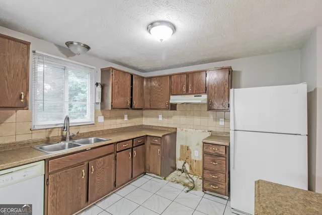 a kitchen with a sink a refrigerator and cabinets