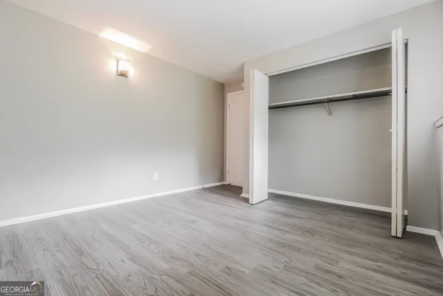 a view of an empty room with wooden floor and closet