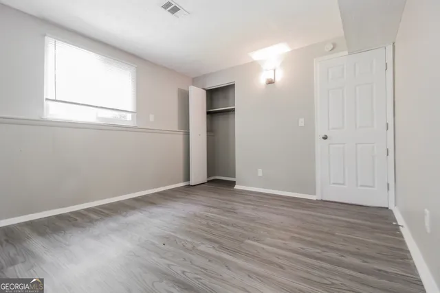 an empty room with wooden floor and windows