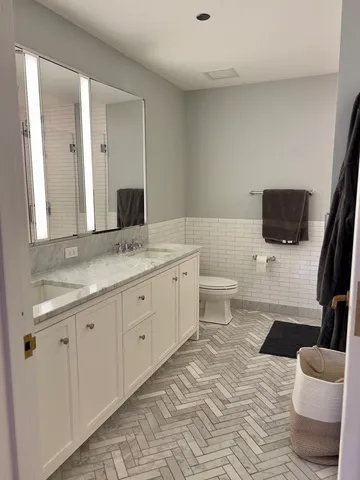 a spacious bathroom with a granite countertop toilet sink and mirror