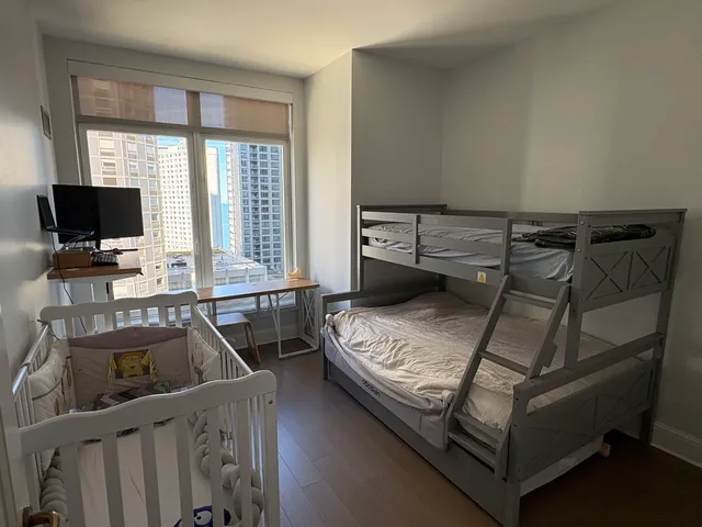 a bedroom with a bed and a flat tv screen next to a window