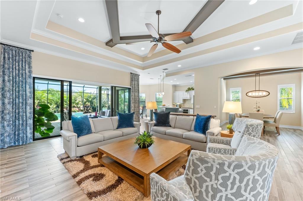 Living room with ornamental molding, a ceiling fan, recessed lighting, light wood finished floors, and arched walkways