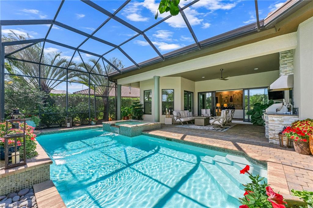 6818 Canwick Cove Circle Naples, FL 34113 - Photo 20 of 44 Combined pool / hot tub featuring a lanai, an outdoor kitchen with living area, a patio, and a sunroom