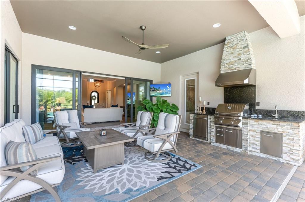 6818 Canwick Cove Circle Naples, FL 34113 - Photo 24 of 44 View of patio featuring a ceiling fan, an outdoor kitchen and area to lounge, and a fire pit