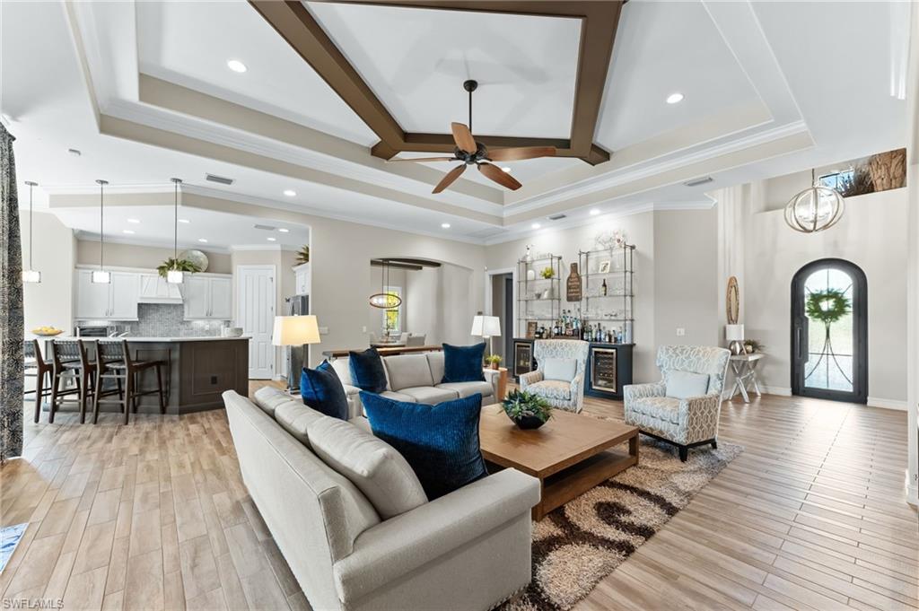 6818 Canwick Cove Circle Naples, FL 34113 - Photo 3 of 44 Living area with arched walkways, crown molding, light wood-style floors, beverage cooler, and recessed lighting