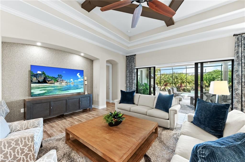 6818 Canwick Cove Circle Naples, FL 34113 - Photo 4 of 44 Living area with wood finished floors, ornamental molding, ceiling fan, arched walkways, and an accent wall