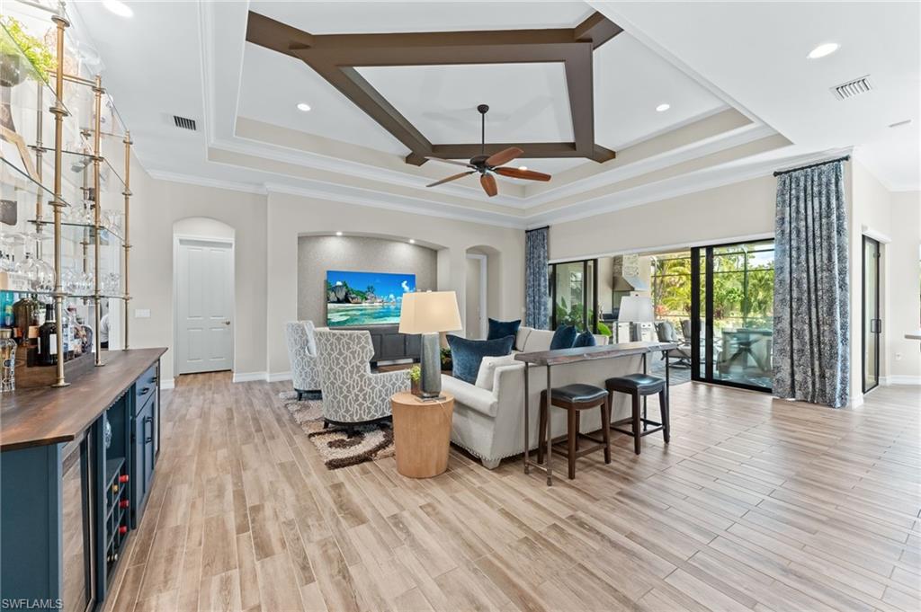 6818 Canwick Cove Circle Naples, FL 34113 - Photo 5 of 44 Living room featuring coffered ceiling, arched walkways, ornamental molding, a bar, and recessed lighting