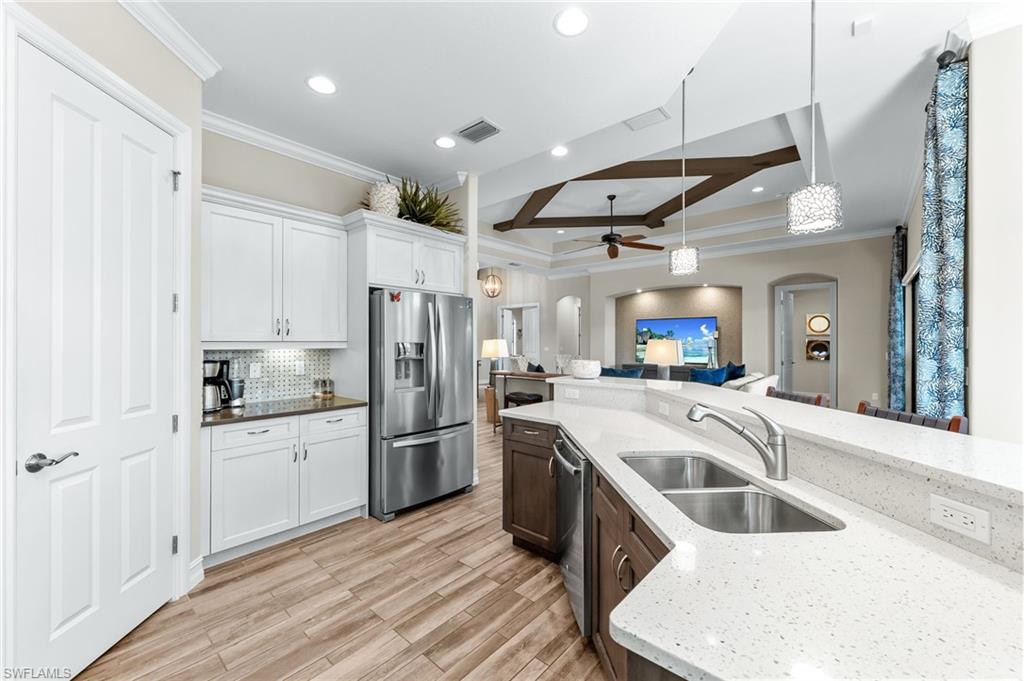 6818 Canwick Cove Circle Naples, FL 34113 - Photo 9 of 44 Kitchen featuring arched walkways, stainless steel appliances, hanging light fixtures, a ceiling fan, and ornamental molding