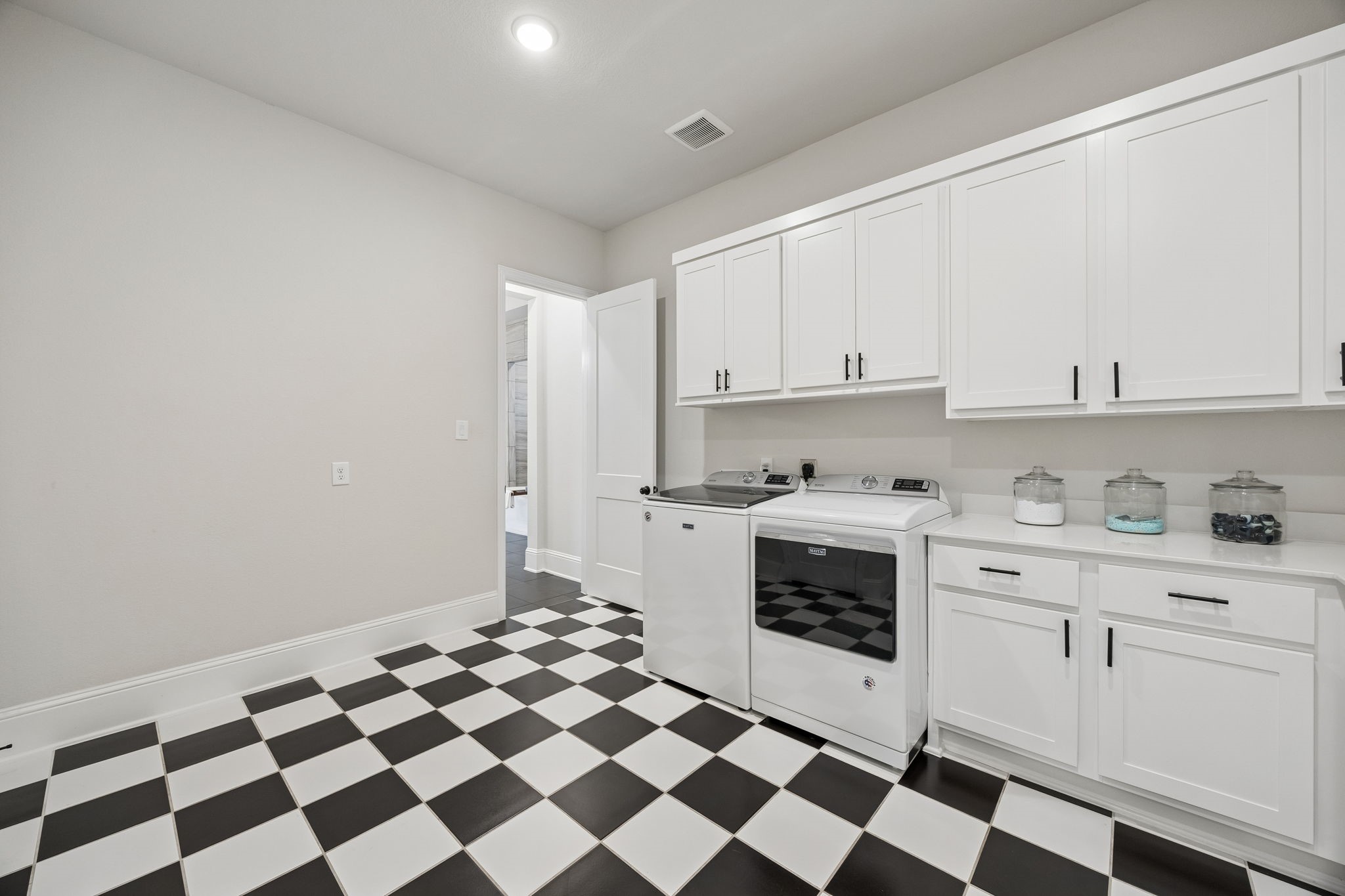 10102 South Goshawk Trail Conroe, TX 77385 - Photo 33 of 46 a kitchen with a checkered floor and white cabinets