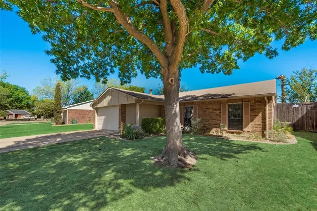 a view of a house with a yard and large trees