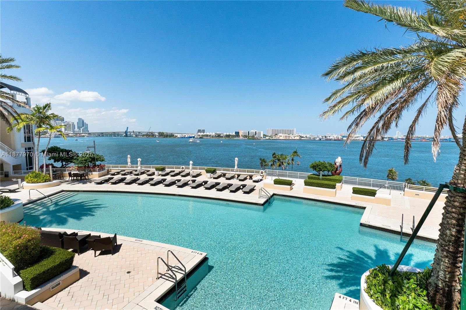 848 Brickell Key Drive, Unit 2502 Miami, FL 33131 - Photo 30 of 40 a view of a swimming pool and lounge chairs in back yard of the house