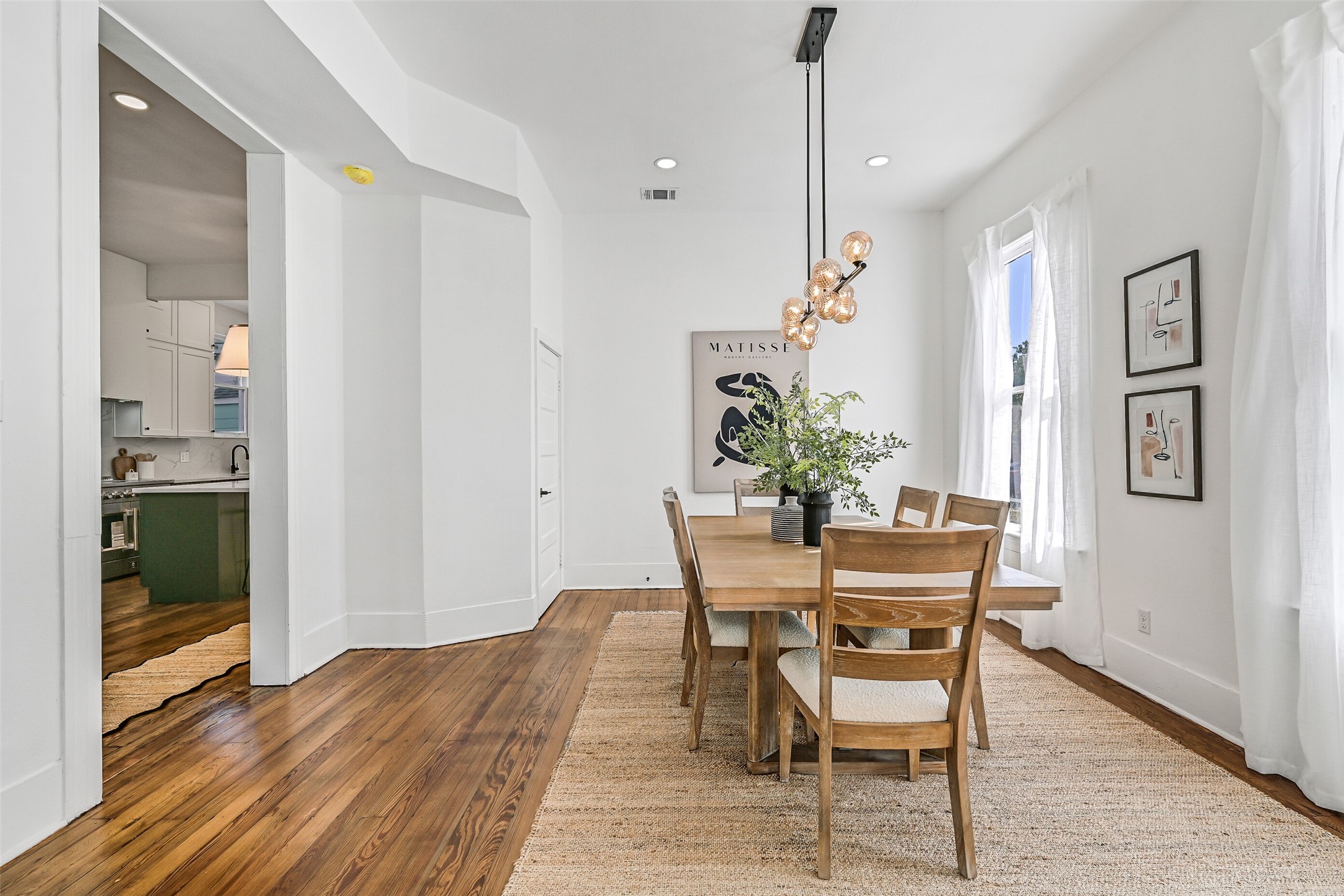 2010 Rosenberg Street Galveston, TX 77550 - Photo 11 of 50 From the living room, your eyes are drawn to the dining room beyond — open, elegant, and seamlessly connected. A pendant light casts a soft, inviting glow that transforms mealtime into an experience. Picture dinner parties where conversations flow as easily as the coastal breeze, with off-street parking for guests just outside. The layout makes entertaining effortless and everyday living feel luxuriously joyful.