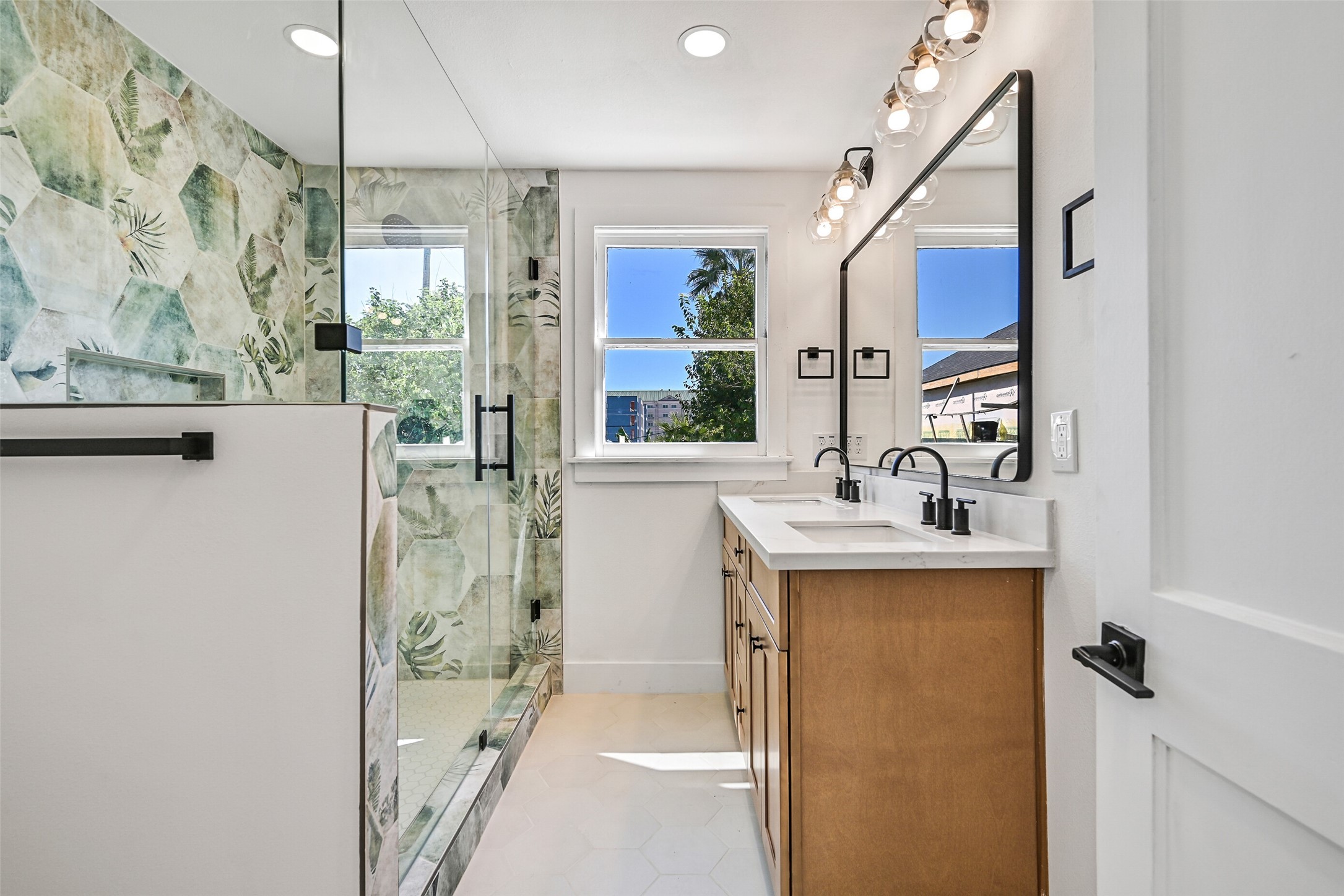 2010 Rosenberg Street Galveston, TX 77550 - Photo 28 of 50 The primary bathroom feels like a serene retreat — dual vanities, glass-enclosed shower, and elegant tilework create a spa-inspired experience. Every fixture, finish, and hardware piece was thoughtfully chosen to balance comfort and style. It’s a place to unwind, recharge, and start every day refreshed. Luxury meets coastal relaxation here, with light, texture, and design flowing together perfectly!