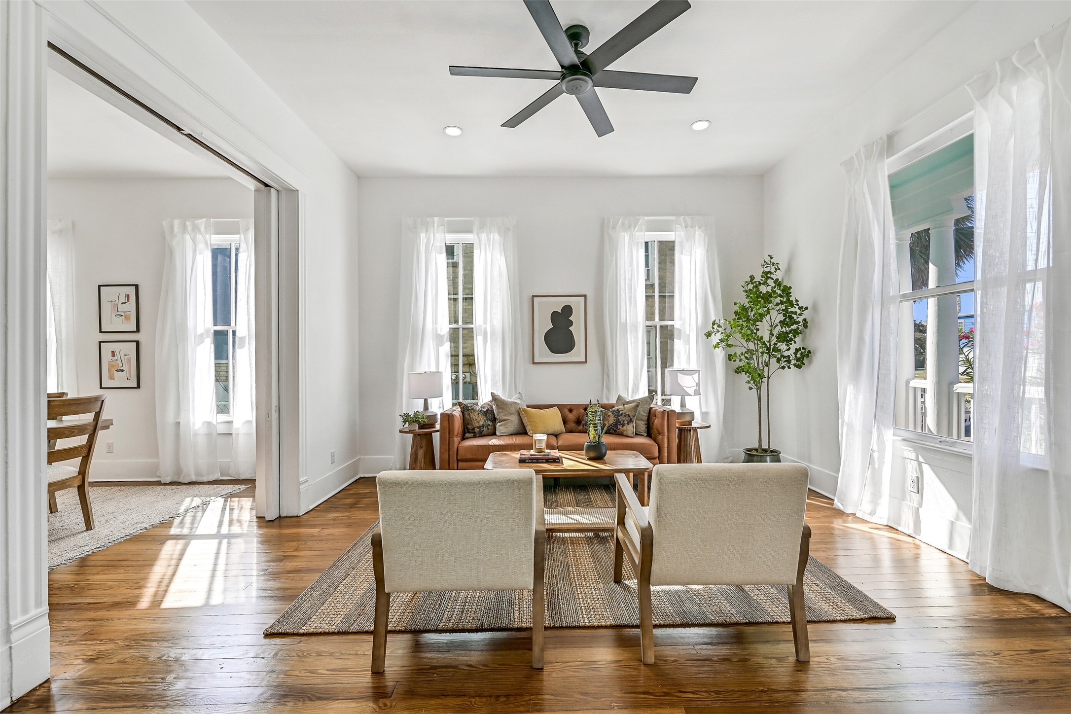 2010 Rosenberg Street Galveston, TX 77550 - Photo 10 of 50 This view captures the seamless harmony of the main living area — where natural light, open flow, and reworked original windows create a vibrant yet relaxing atmosphere. Gather friends for parade day, unwind after a sunny beach afternoon, or savor a quiet evening surrounded by warm wood tones and updated lighting. Every finish, every detail is designed for connection and comfort — a perfect balance of energy, elegance, and easy island living!