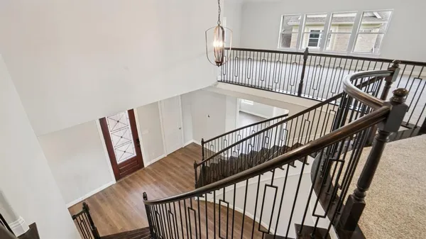 an empty room with wooden floor chandelier and windows