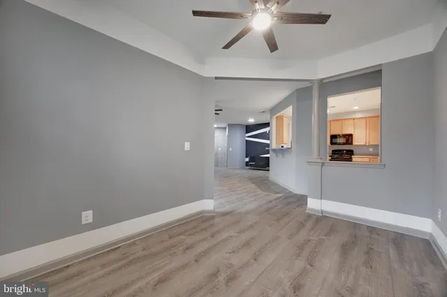 an empty room with wooden floor and a ceiling fan