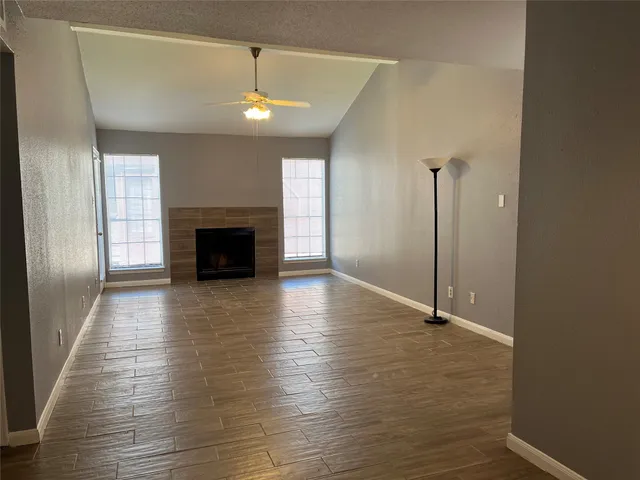 an empty room with wooden floor fireplace and windows