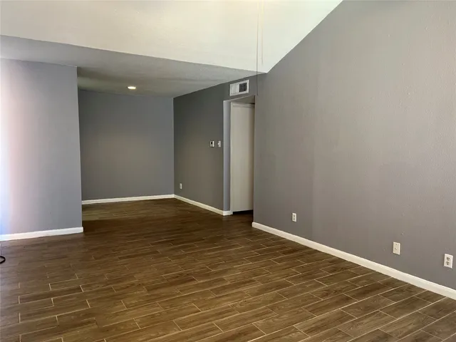 a view of an empty room with wooden floor and closet