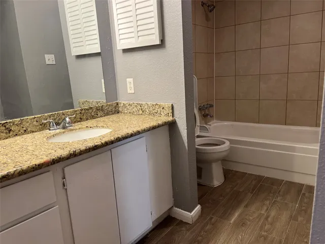 a bathroom with a granite countertop toilet a sink and a bathtub