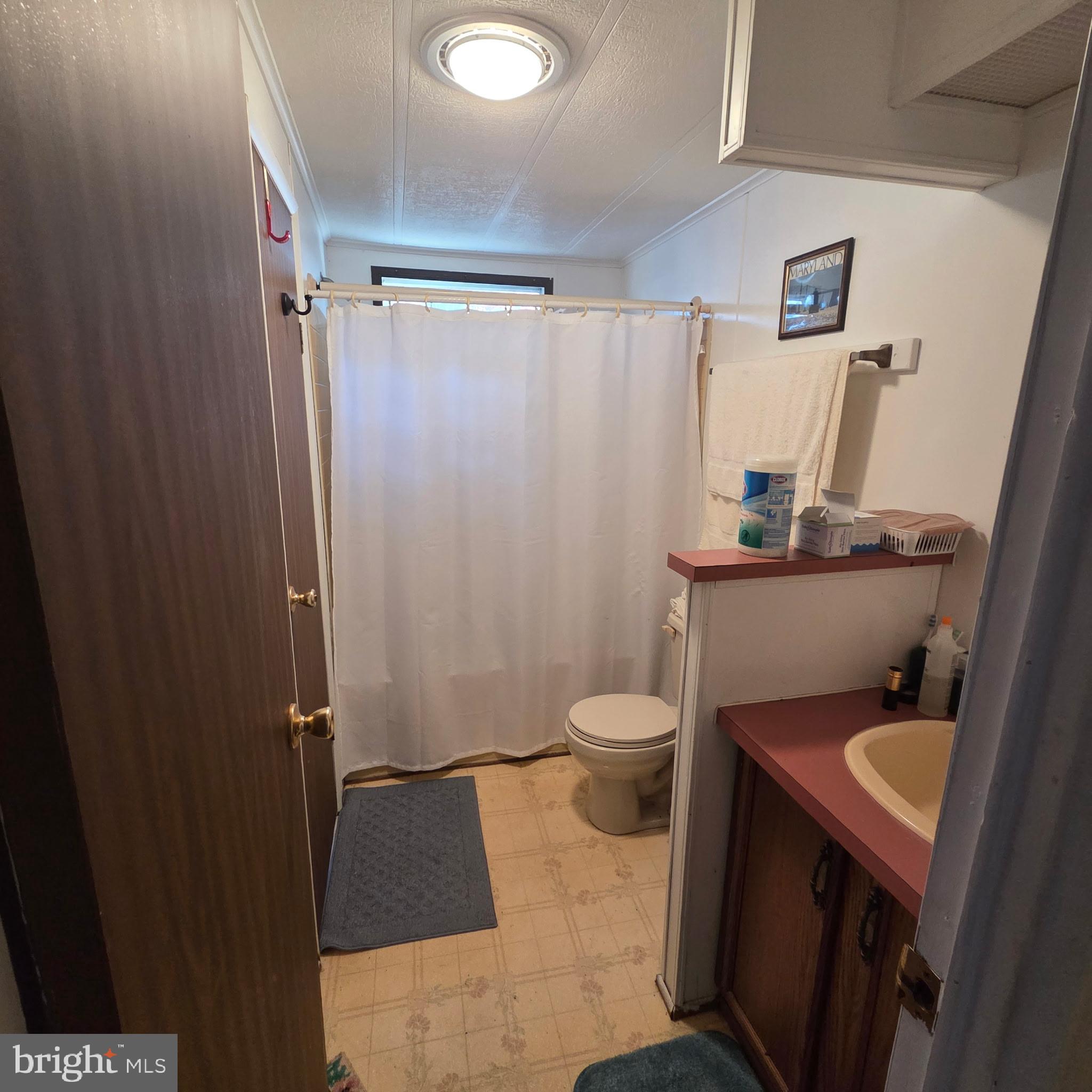 12623 Shell Mill Road, Unit 123 Bishopville, MD 21813 - Photo 11 of 15 a white toilet sitting next to a bathroom sink and vanity
