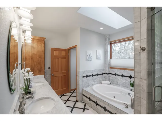 a bathroom with a sink double vanity granite tub shower and a mirror